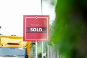 A red sold sign sitting on the side of a road